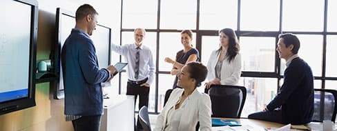 people in a conference room collaborating on an interactive flat panel display