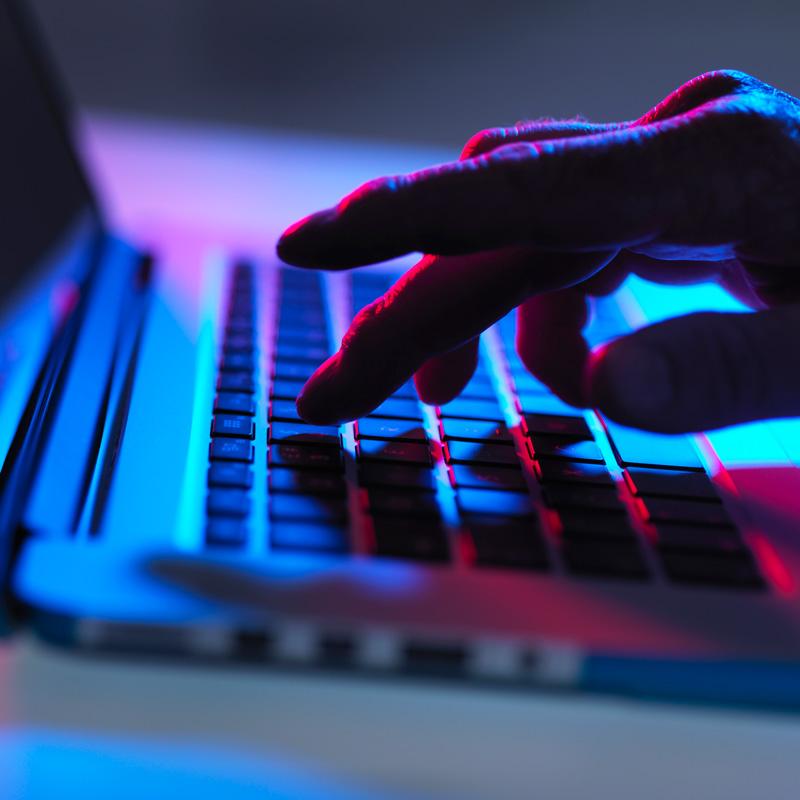 finger typing on a keyboard in low light