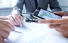 three people in a meeting reviewing documents and tablet