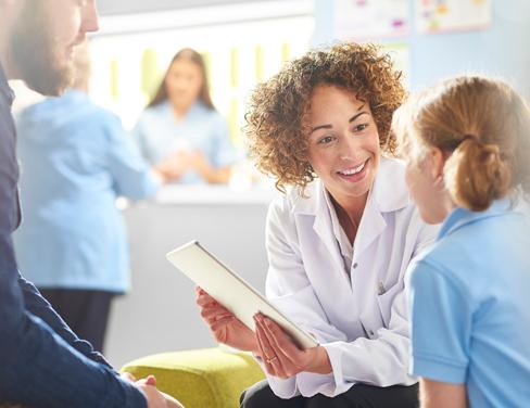 Doctor with a tablet speaking with young child