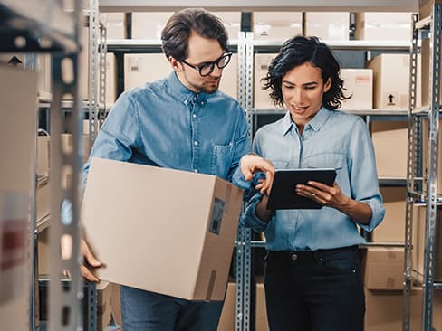 workers shipping boxes while using a tablet