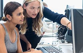 woman assisting another woman at a computer workstation