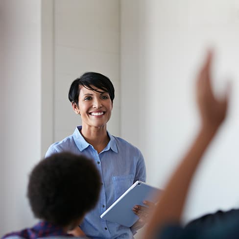 Smiling professor in classroom with hand raises