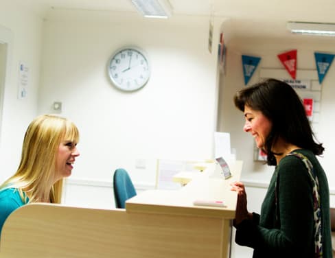 Clinic receptionist helping patient.