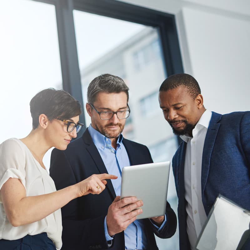 three colleagues having a discussion and referencing information on a tablet