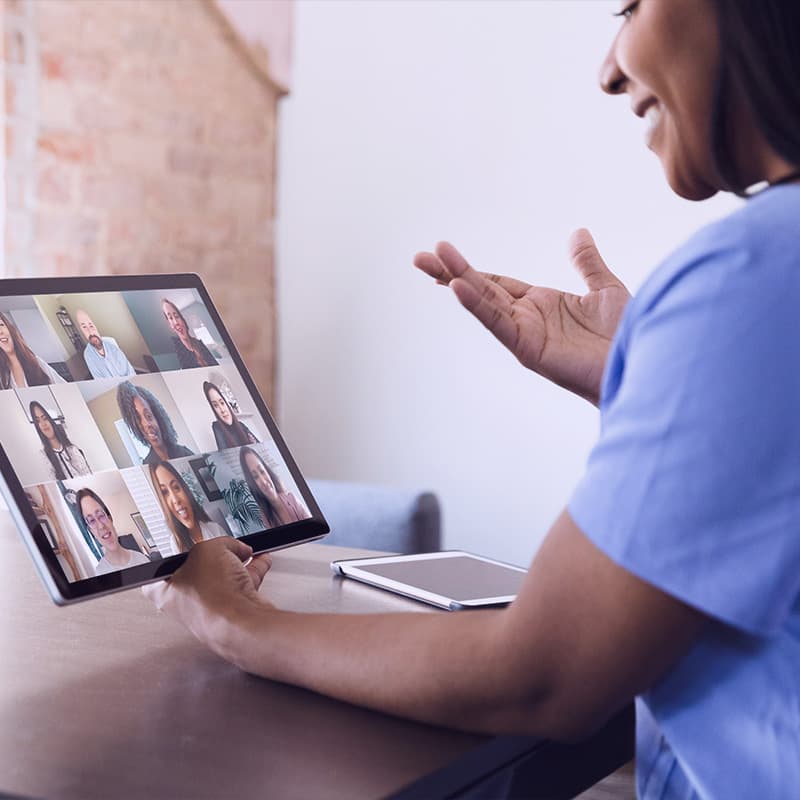A confident female healthcare professional gestures as she talks with a medical team via video conference