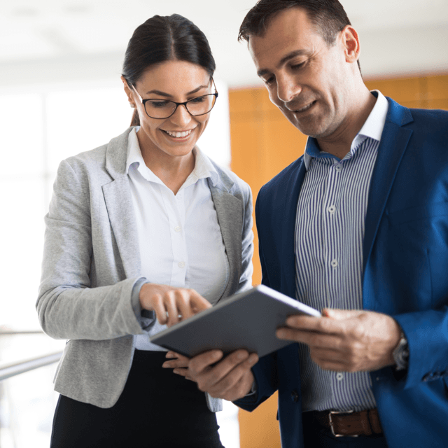 Business man and woman happy looking at tablet