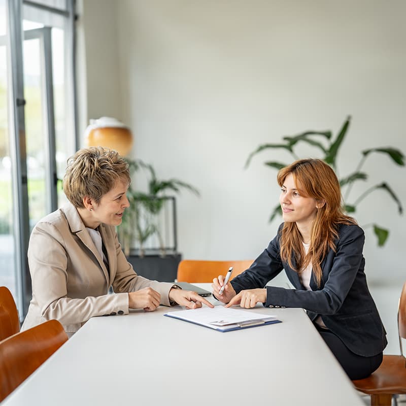 A middle aged and young professional chatting, demonstrating how human resources team helps create a culture of excellence.