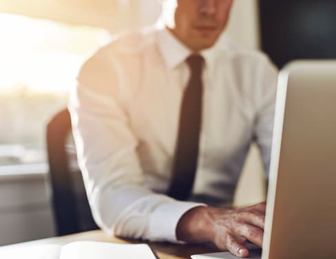 Ricoh professional in white shirt and tie at desk with computer
