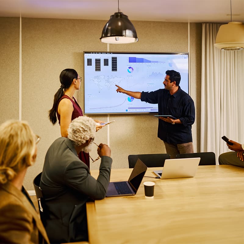 Corporate team analyzing charts and reports during a meeting, illustrating marketing strategy, communications, and data-driven decision making.