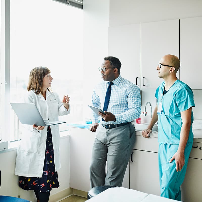 Female doctor leading medical team discussion in hospital exam room