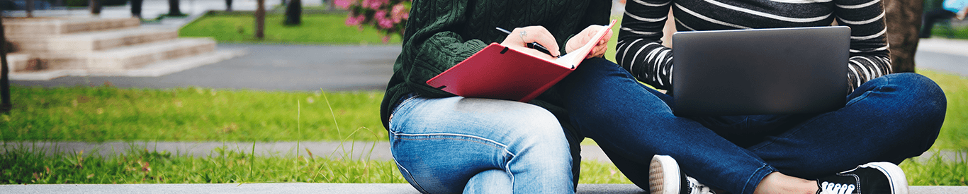 Photo of students sitting using a laptop.