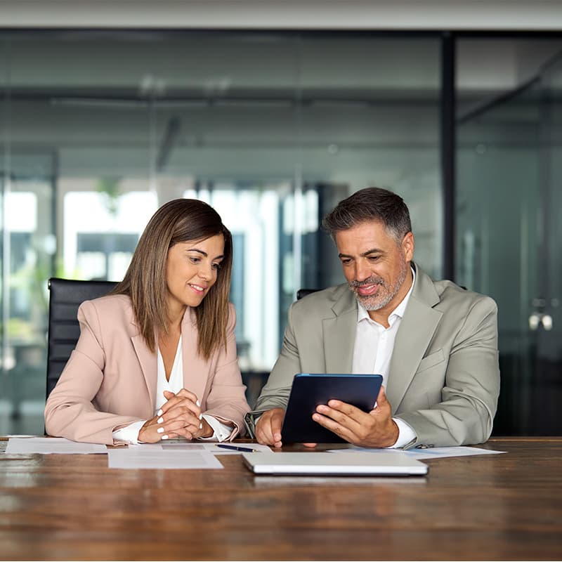 Two business professionals reviewing a document on a tablet, demonstrating how our direct sales team focuses on Enterprise, Targeted, SLG, K12 customers and assigned ZBA sales opportunities.