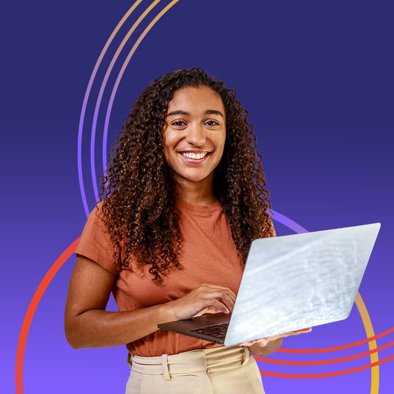 A smiling woman with curly brown hair, standing with a laptop enjoying a flexible work and employee experience