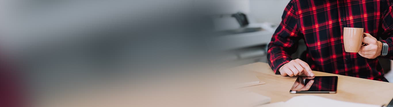 Selective focus of a tablet being used by a man with large format printer in background